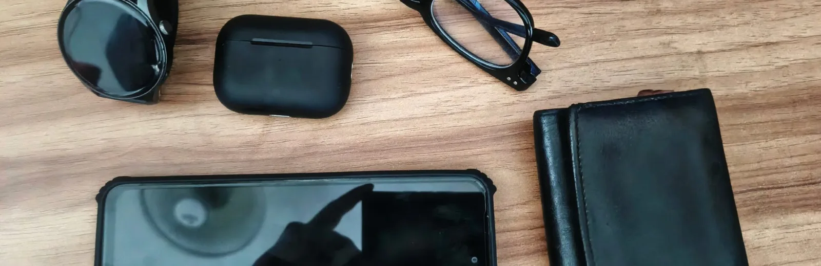 Draadloze oordopjes, telefoon en accessoires op een houten tafel