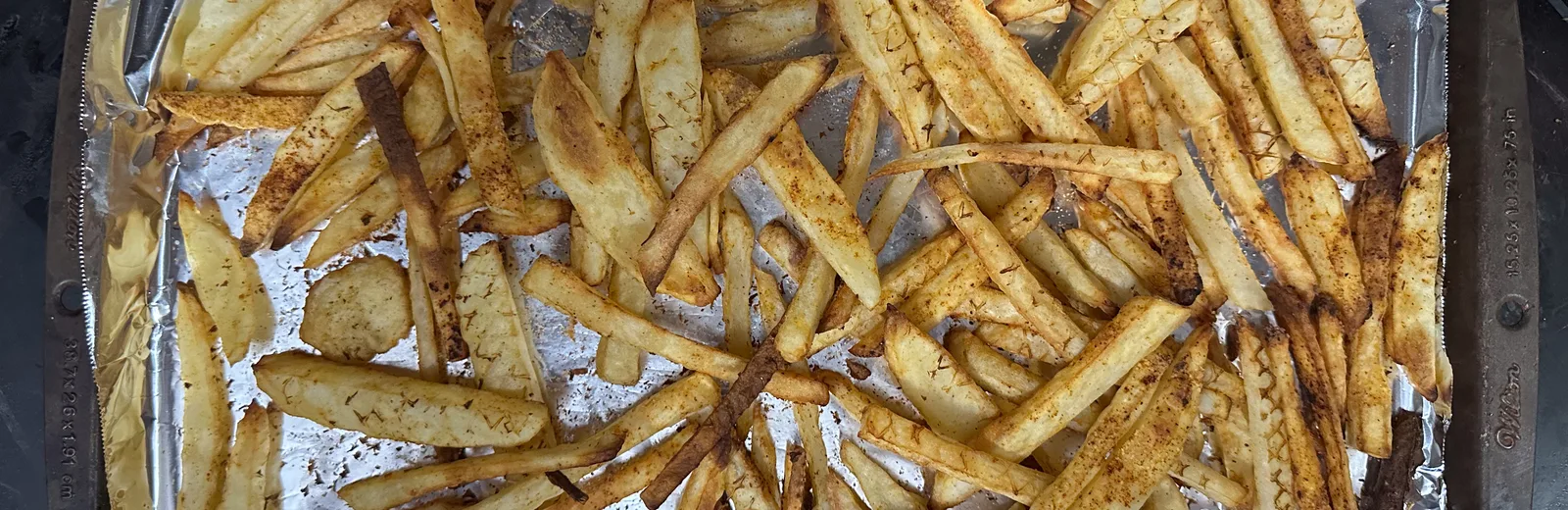Goudbruine frietjes vers uit de airfryer op een bakplaat